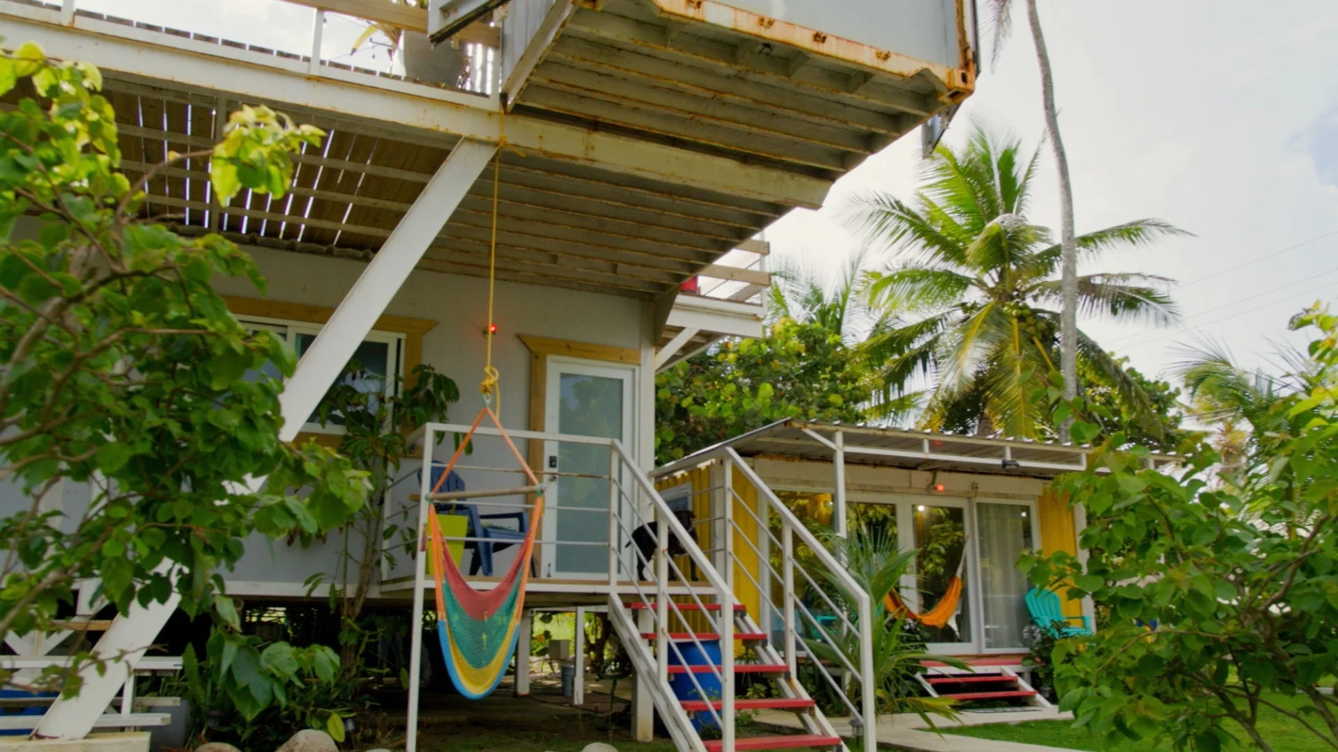 DK Backyard: los módulos de alojamiento entre palmas, con hamacas y escaleras de colores.